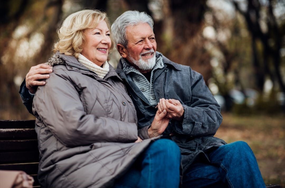 An elderly couple sitting together outside