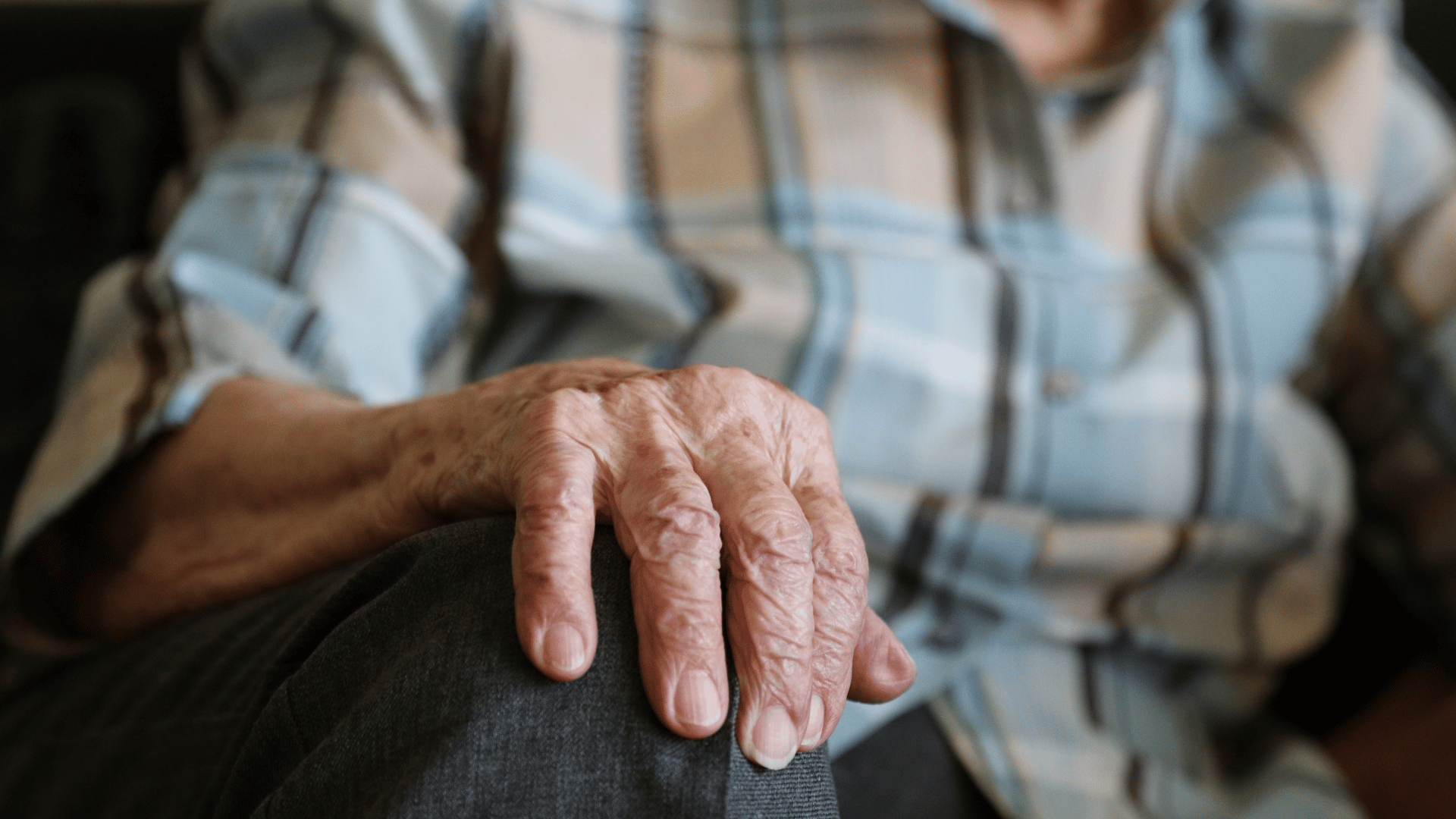 Close up of an older person's hand resting on their lap