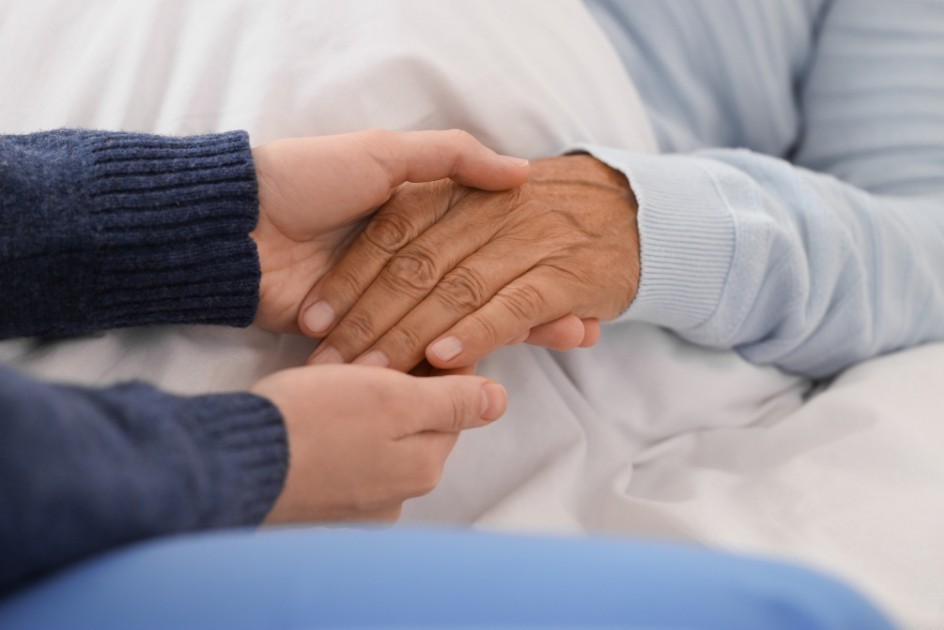 Young person holding the hand of an elderly person